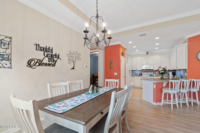 dining space featuring ornamental molding, light hardwood / wood-style floors, and a notable chandelier