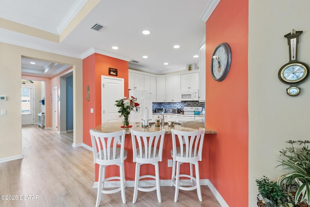 310 Coral Reef Way, Daytona Beach, FL 32124 - kitchen featuring white appliances, a kitchen breakfast bar, a peninsula, light stone countertops, and white cabinetry