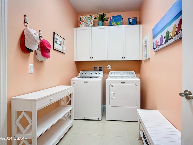 laundry area with washing machine and dryer, cabinets, and light tile patterned floors