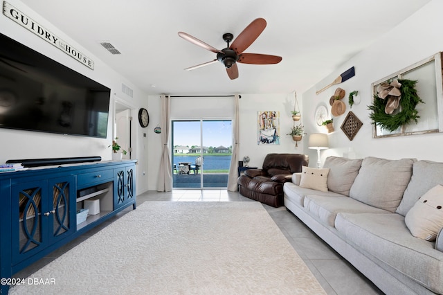 tiled living room with ceiling fan and a water view