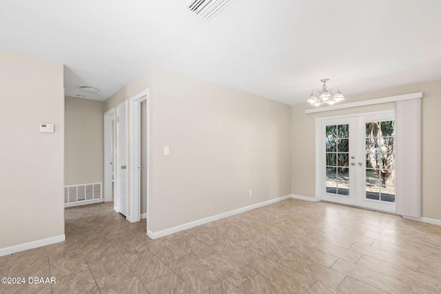 spare room with french doors and an inviting chandelier