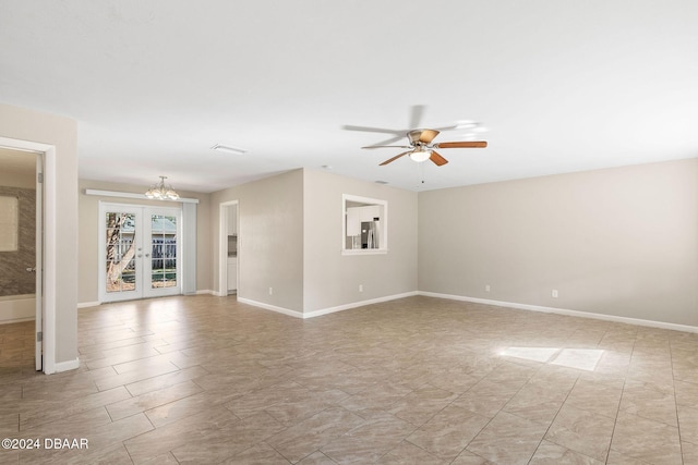 spare room featuring ceiling fan with notable chandelier and french doors