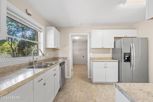 kitchen featuring white cabinets, stainless steel appliances, light stone countertops, and sink