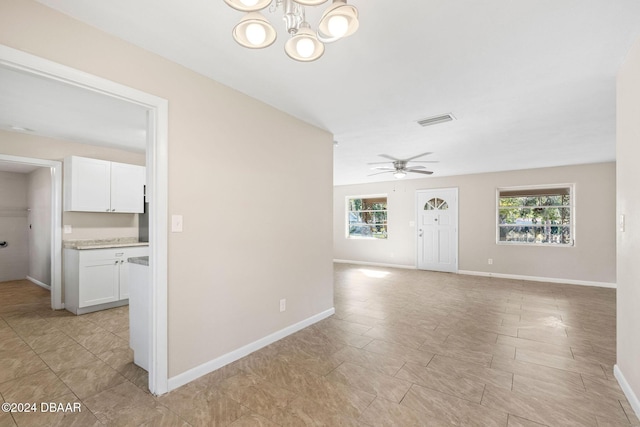 empty room with ceiling fan with notable chandelier