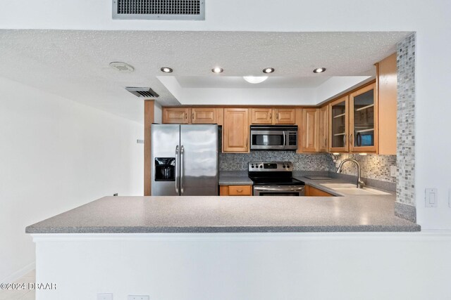 kitchen with backsplash, sink, a textured ceiling, appliances with stainless steel finishes, and kitchen peninsula