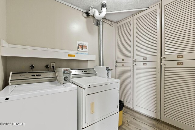 laundry room featuring light wood-type flooring, a textured ceiling, and washing machine and dryer