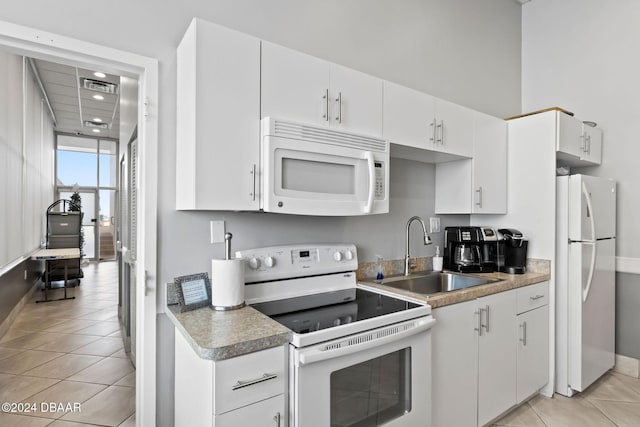 kitchen featuring sink, white cabinets, white appliances, and light tile patterned floors