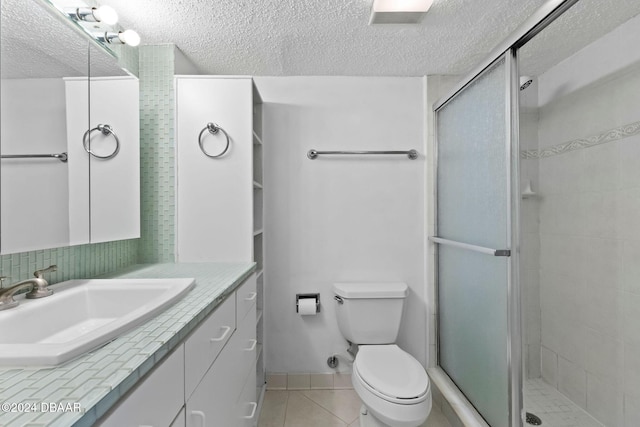 bathroom with vanity, tile patterned flooring, toilet, a textured ceiling, and walk in shower