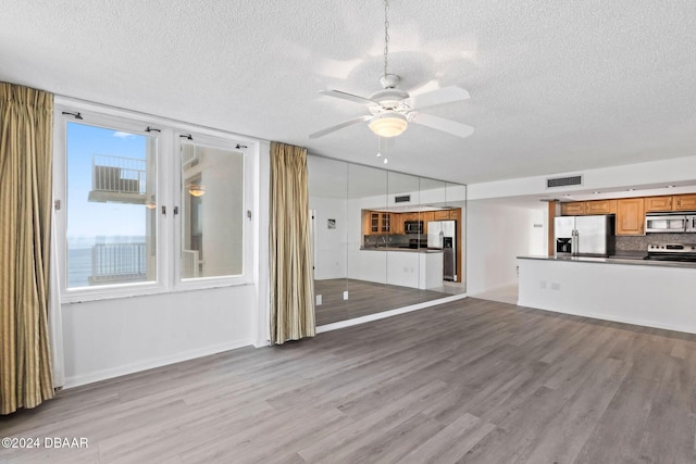 unfurnished living room featuring ceiling fan, light hardwood / wood-style flooring, and a textured ceiling