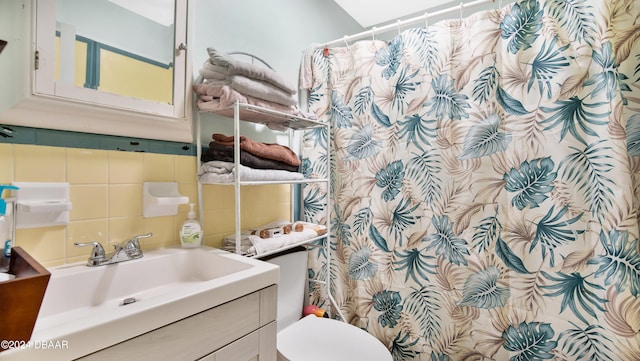 bathroom with toilet, vanity, backsplash, and tile walls