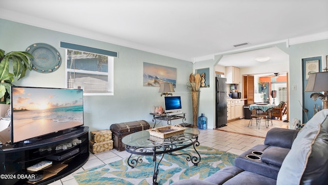 tiled living room with ceiling fan and crown molding