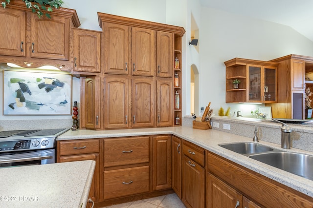 kitchen featuring light stone counters, light tile patterned flooring, stainless steel stove, sink, and lofted ceiling