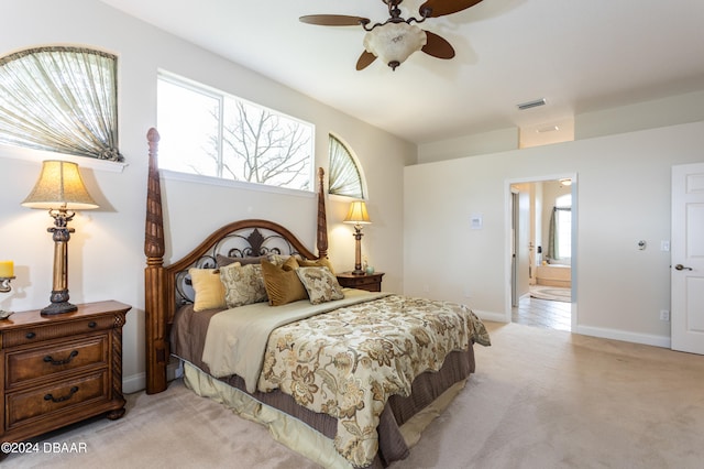 bedroom with ensuite bathroom, light carpet, and ceiling fan