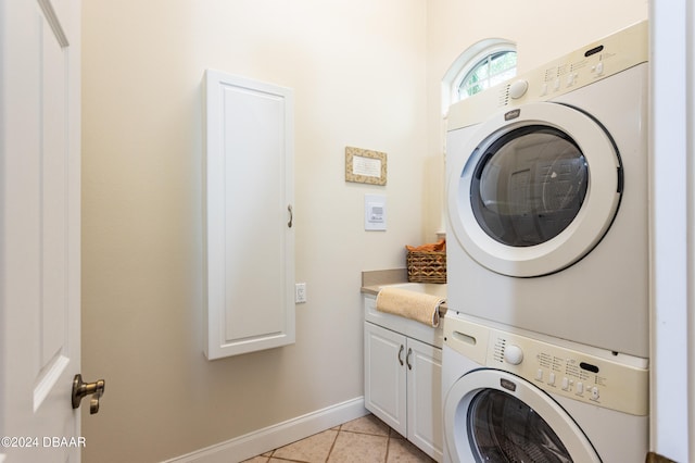 clothes washing area featuring cabinets, stacked washer / drying machine, and light tile patterned floors