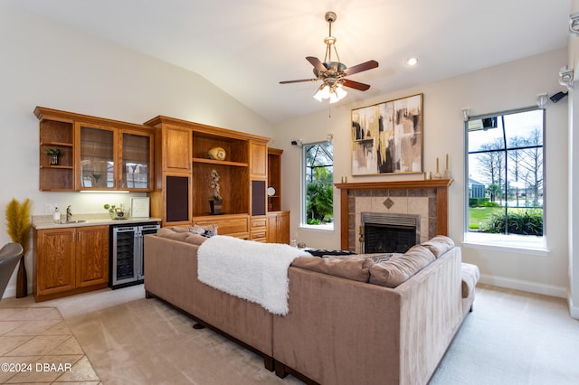 living room with light colored carpet, lofted ceiling, sink, a fireplace, and wine cooler