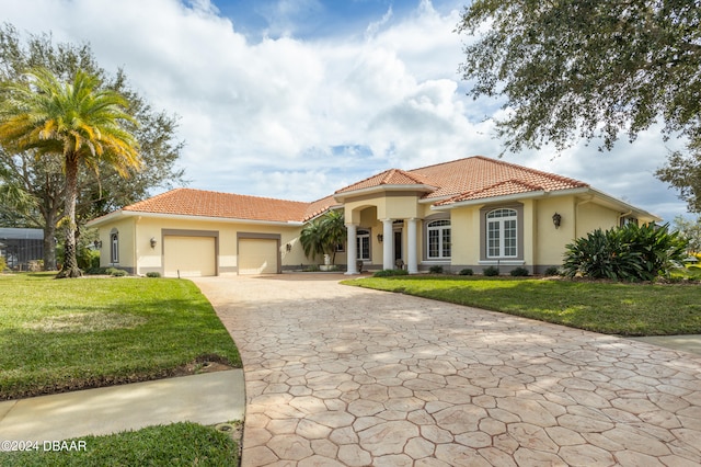 mediterranean / spanish-style house featuring a garage and a front lawn