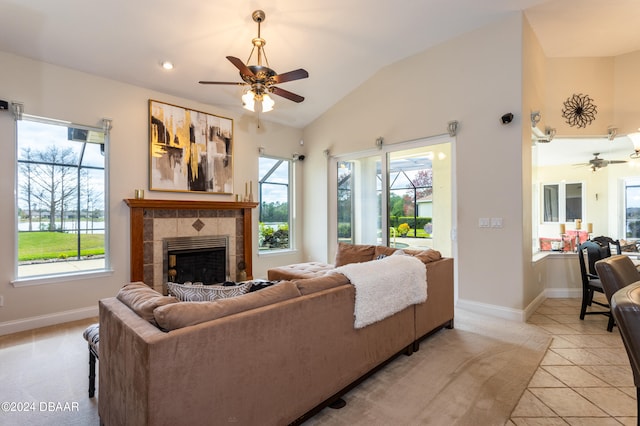 tiled living room with plenty of natural light, ceiling fan, vaulted ceiling, and a tile fireplace