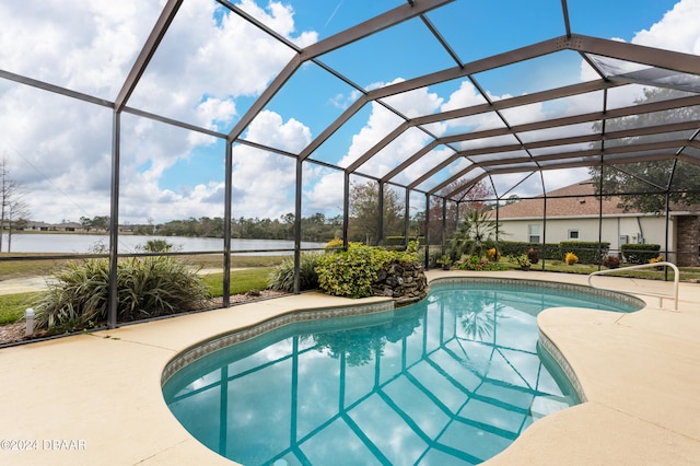 view of pool with glass enclosure, a patio area, and a water view