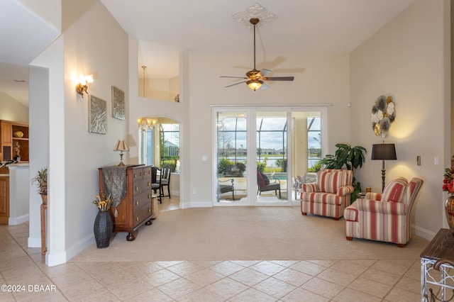 living room with ceiling fan with notable chandelier, light carpet, and high vaulted ceiling