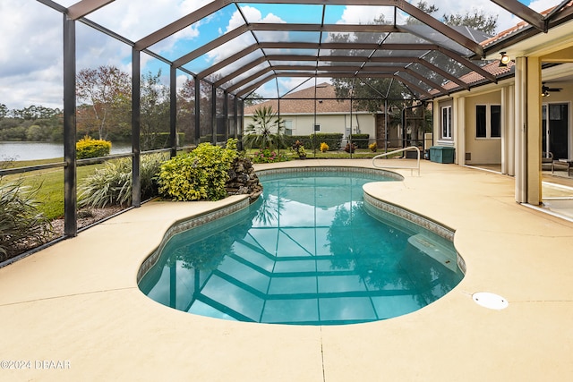 view of swimming pool with glass enclosure, a patio area, a water view, and ceiling fan