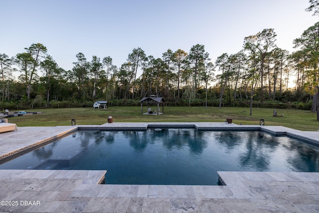 pool at dusk with a lawn, a gazebo, and a patio area