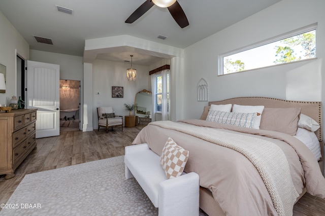 bedroom with ceiling fan with notable chandelier and light wood-type flooring