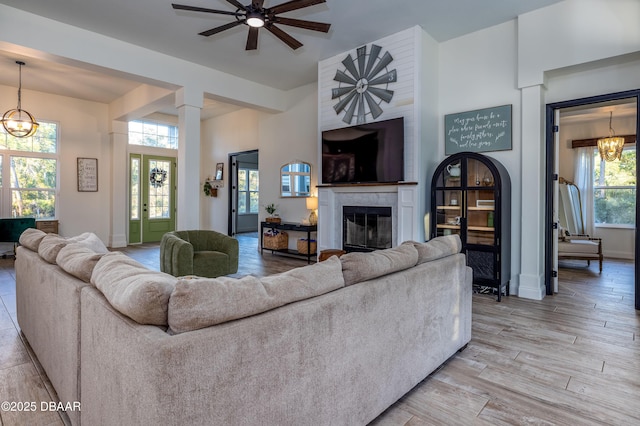 living room with ceiling fan with notable chandelier and a fireplace