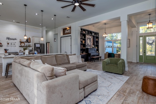 living room with ceiling fan with notable chandelier and built in shelves