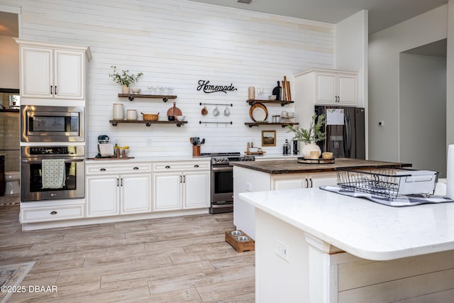 kitchen with appliances with stainless steel finishes, white cabinets, and a center island