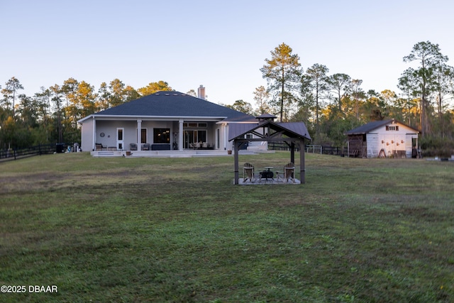 back of property featuring a gazebo, a yard, and a storage shed