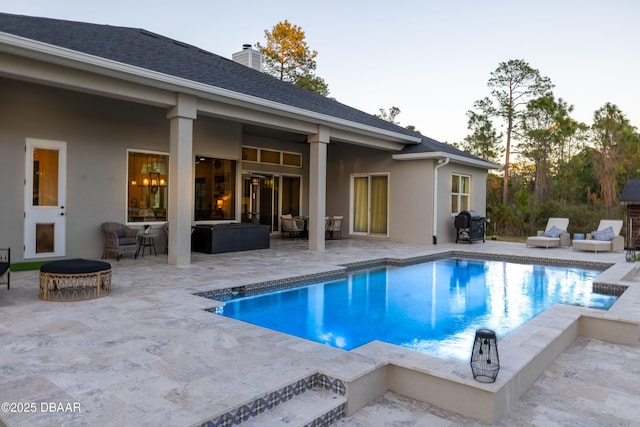 pool at dusk featuring a patio area and an outdoor living space with a fireplace