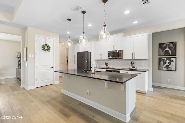 1602 Killian Drive Ne, Palm Bay, FL 32905 - kitchen featuring stainless steel microwave, dark countertops, fridge, a center island with sink, and decorative backsplash