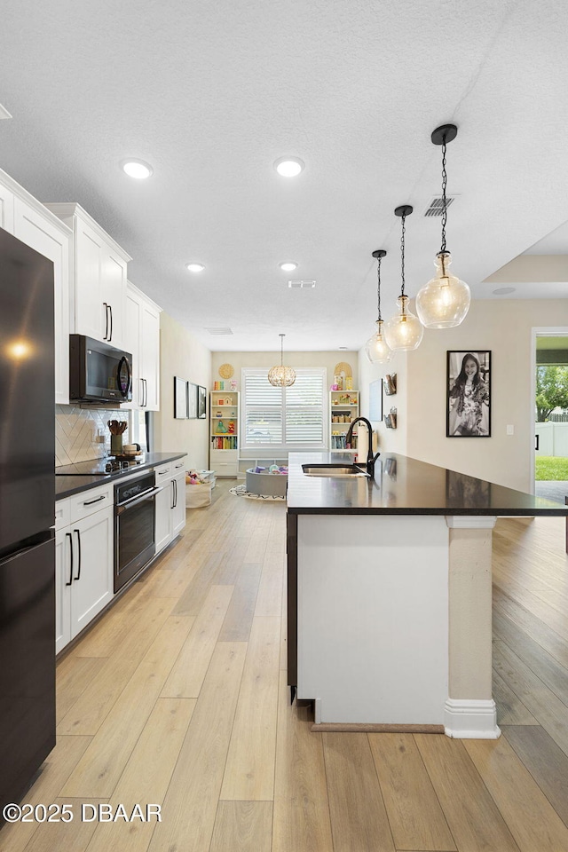 1602 Killian Drive Ne, Palm Bay, FL 32905 - kitchen with black appliances, dark countertops, recessed lighting, white cabinetry, and an island with sink
