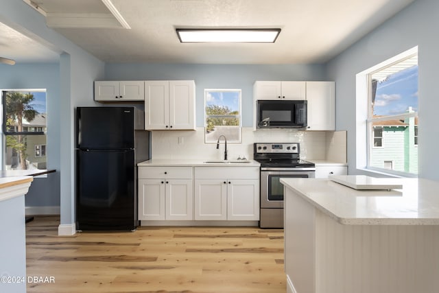 kitchen with black appliances, light wood-type flooring, white cabinetry, and sink