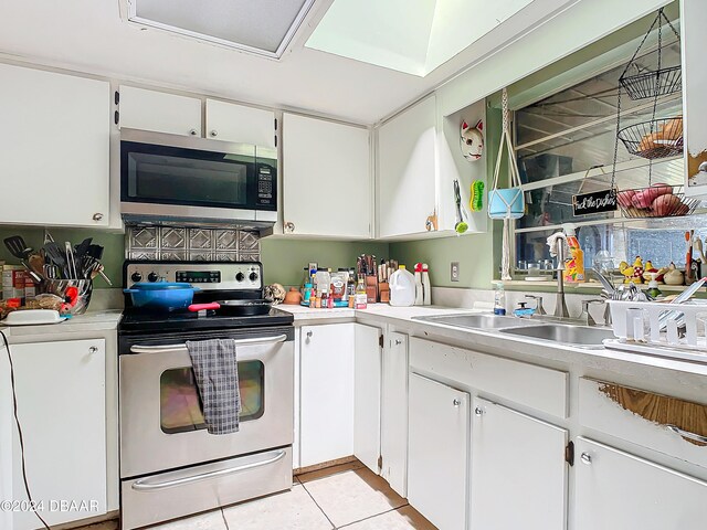 kitchen with white cabinetry, sink, light tile patterned flooring, and electric range oven