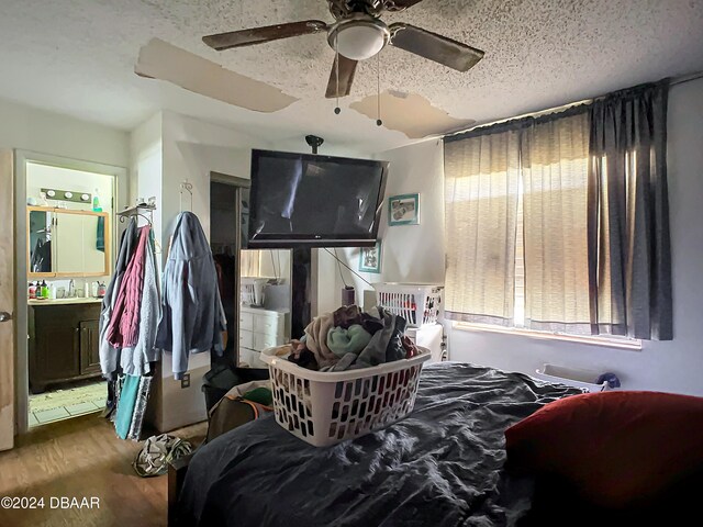 bedroom with hardwood / wood-style floors, ceiling fan, ensuite bath, and a textured ceiling