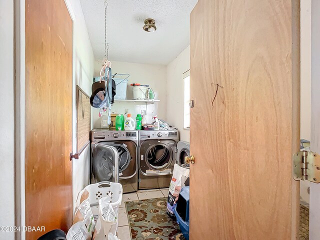 laundry area with washing machine and clothes dryer, tile patterned floors, and a textured ceiling