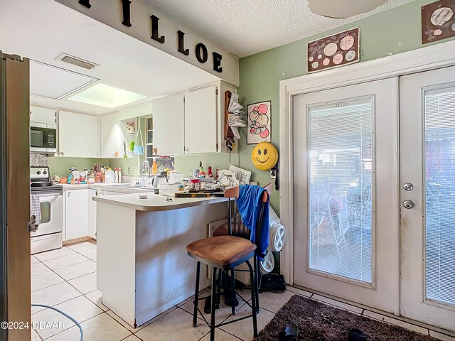 kitchen featuring white cabinetry, a breakfast bar area, light tile patterned floors, and white range with electric cooktop