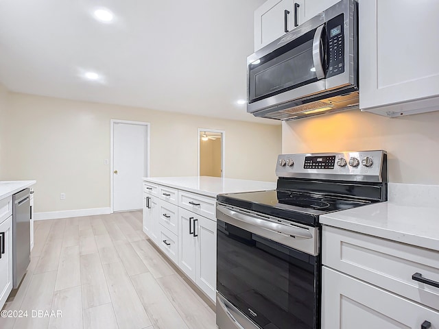 kitchen with white cabinetry, stainless steel appliances, light stone counters, and light hardwood / wood-style flooring