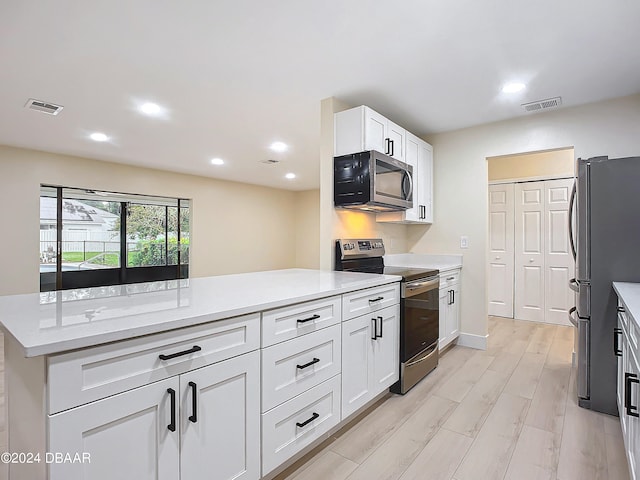 kitchen featuring light stone countertops, appliances with stainless steel finishes, light hardwood / wood-style floors, and white cabinets