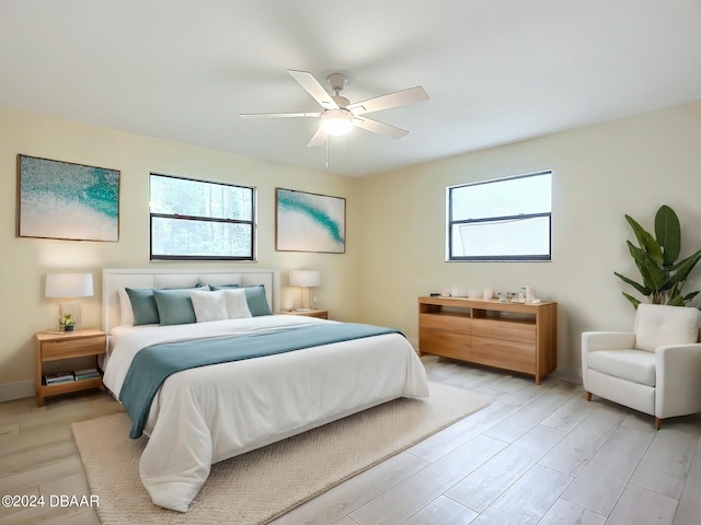 bedroom featuring ceiling fan, multiple windows, and light hardwood / wood-style floors