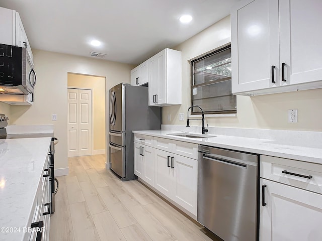 kitchen featuring white cabinetry, stainless steel appliances, sink, and light stone counters