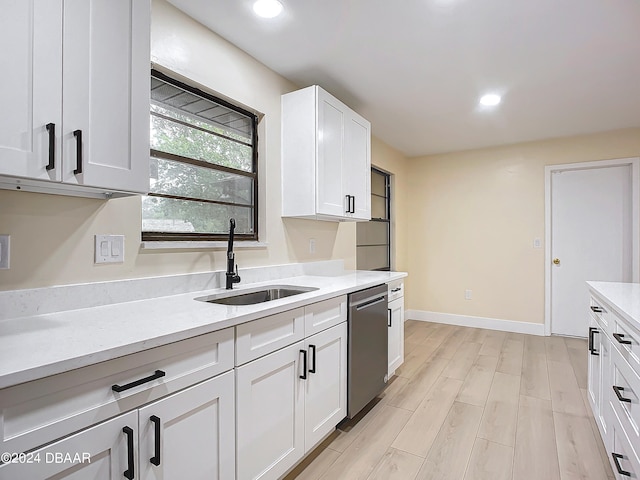 kitchen featuring stainless steel dishwasher, white cabinetry, sink, and light hardwood / wood-style flooring