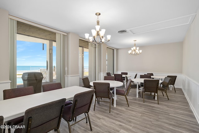 dining space featuring light wood-type flooring, a chandelier, and a water view