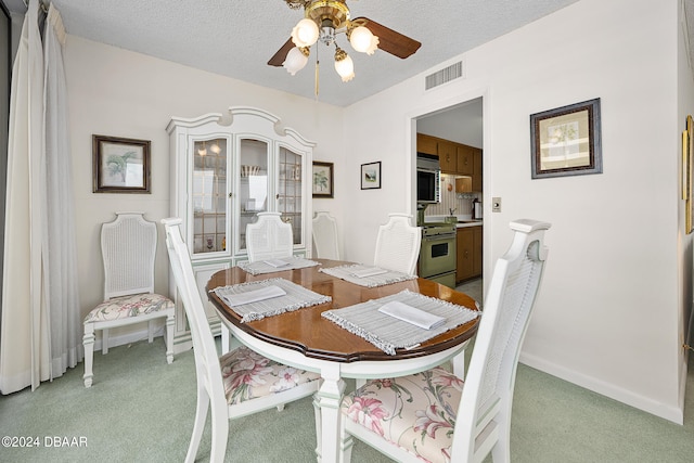 dining room featuring light carpet, a textured ceiling, and ceiling fan