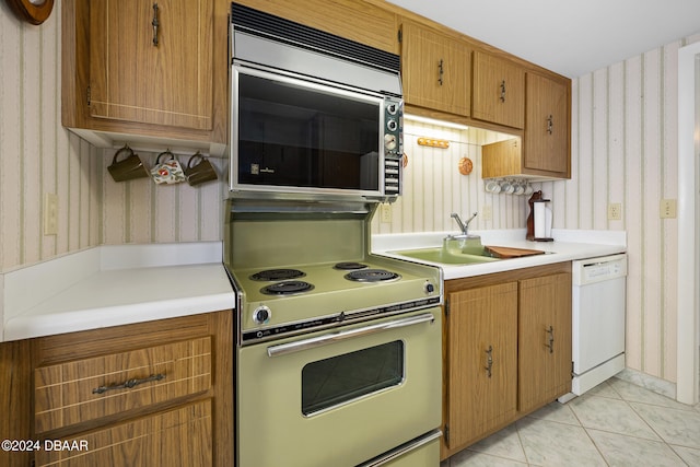 kitchen with dishwasher, range with electric stovetop, sink, and light tile patterned floors