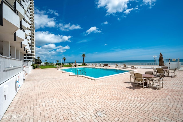 view of swimming pool with a water view and a patio area