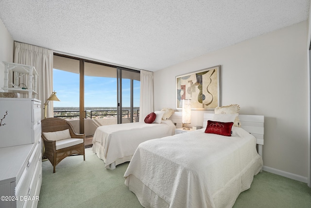 carpeted bedroom featuring a wall of windows and a textured ceiling