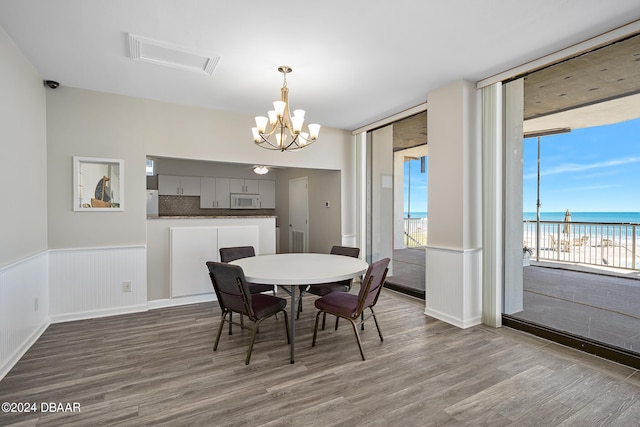 dining space with a water view, hardwood / wood-style flooring, and a chandelier