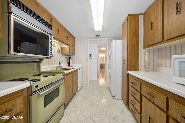 kitchen with white appliances, sink, and light tile patterned floors